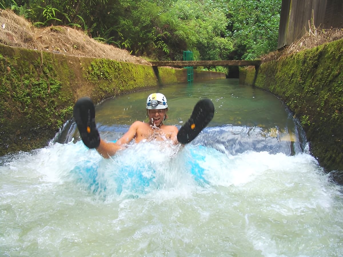 A guest splashing into the water on the Kauai tubing adventure